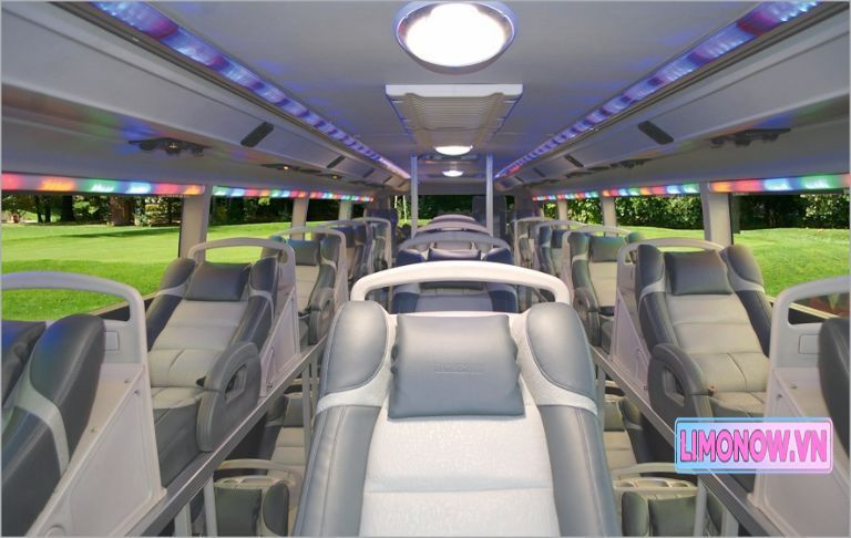 Xe limousine Ford Transit màu xanh đậu ven hồ, nền các tòa nhà hiện đại, dịch vụ xe khách Ninh Bình Thái Nguyên của Limonow.vn