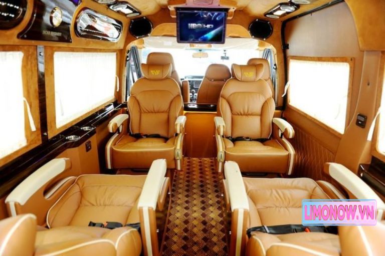 Nội thất xe limousine sang trọng với ghế da màu nâu, trần xe thiết kế hiện đại có đèn LED, màn hình giải trí và các chi tiết gỗ trang trí.