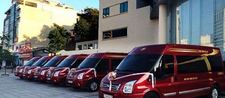 Xe khách hạng thương gia Tuấn Yên màu đen đỏ đậu trước văn phòng, bảng hiệu hiển thị lịch trình và điểm bán vé.