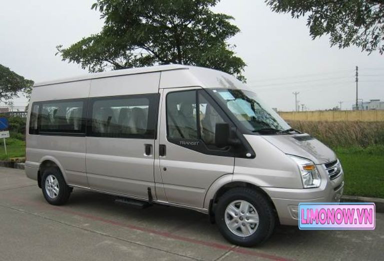 Xe khách Sapa Dragon Express màu xanh đỗ trước Nhà thờ Đá Sapa trong ngày trời mưa